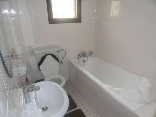 a bathroom with a toilet and a tub and a sink at Larry's Place in Kampala