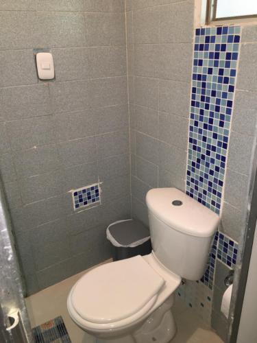 a bathroom with a toilet and a blue tiled wall at Finca La Belleza-Villeta in Villeta