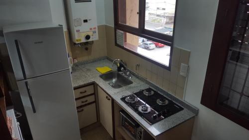 cocina con nevera, fregadero y ventana en CONFORTABLE DEPARTAMENTO CÉNTRICO en Salta