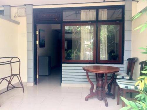 a table and chairs on a porch with a door at Gina's guest house in Sanur