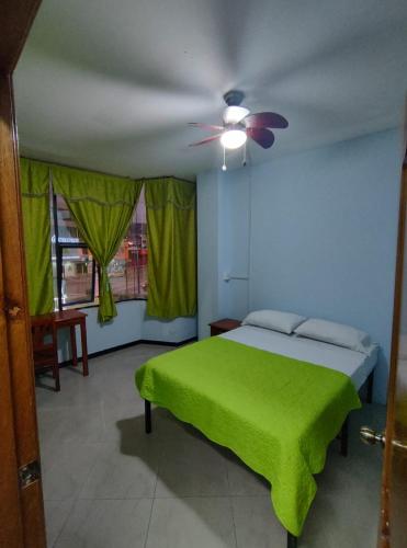 1 dormitorio con cama verde y ventilador de techo en Hostal BAMBU, en Tena
