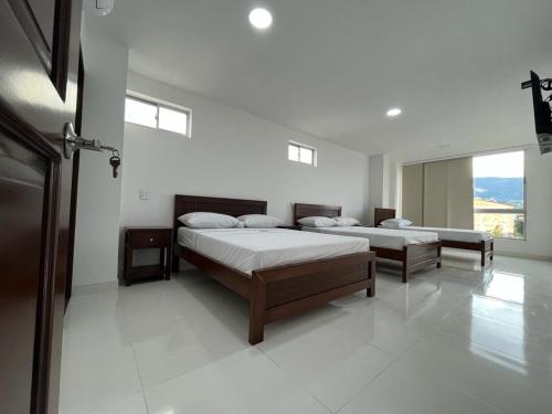 2 camas en una habitación blanca con ventanas en Hotel Plaza Berlín, en Medellín