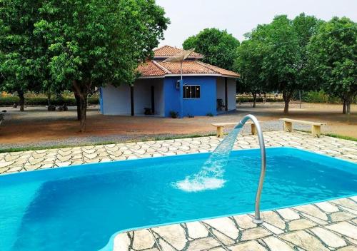 uma piscina com uma fonte de água em frente a uma casa em Pousada Canto das Araras - Vila Bom Jardim Nobres MT em Nobres