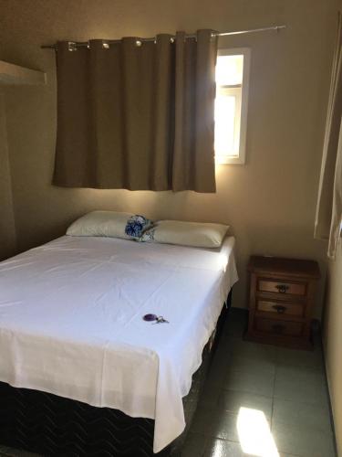 a bedroom with a white bed with a window at Suíte aconchegante na praia in Jacaraípe