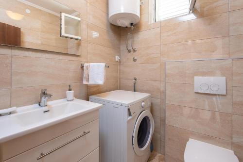 a bathroom with a washing machine and a sink at Holiday Villa Natura in Orebić