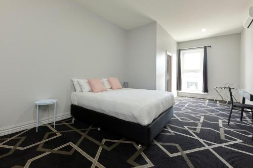 a bedroom with a bed and a table and a chair at Sports Garden Hotel in Launceston