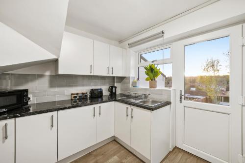 a kitchen with white cabinets and a window at Cosy home in Rochester, sleeps 6 in Strood