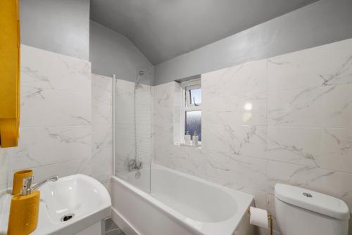 uma casa de banho branca com uma banheira branca e um lavatório. em Cosy home in Rochester, sleeps 6 em Strood