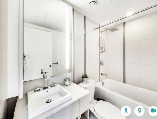 La salle de bains est pourvue d'un lavabo, de toilettes et d'une baignoire. dans l'établissement Comfortable Central Downtown Condo -, à Toronto