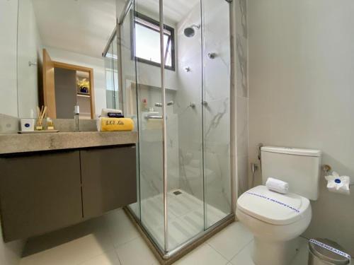 a bathroom with a toilet and a glass shower at Elegante quarto e sala Sky Concept 418 Novissímo in Maceió