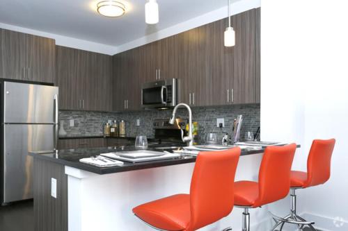 a kitchen with a counter with red chairs and a refrigerator at ViewPoint Suites in Los Angeles