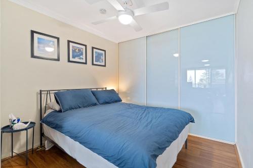 a bedroom with a blue bed and a glass door at Nesuto Apartment Unit 515 in The Entrance