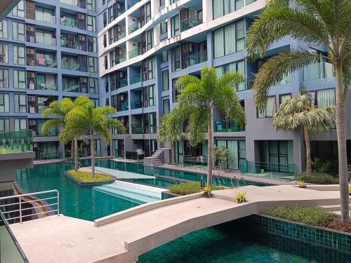 a swimming pool with palm trees in front of a building at Acqua Condominium Jomtien in Jomtien Beach