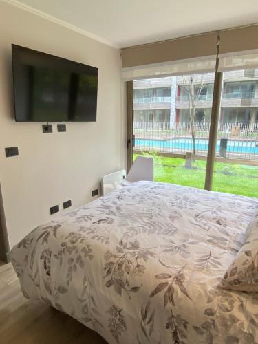 a bedroom with a bed and a flat screen tv at Departamento Pucón, Piscinas, Quincho y Terraza. in Pucón