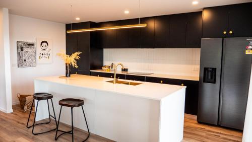 a kitchen with a white counter and black cabinets at Amazing view Architech Home 8Minutes to Hobart CBD in Hobart