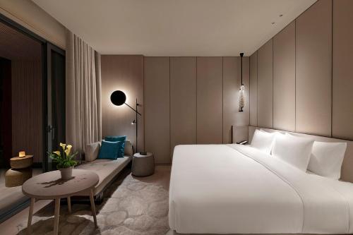 a bedroom with a large white bed and a table at Hotel Indigo Anji in Anji