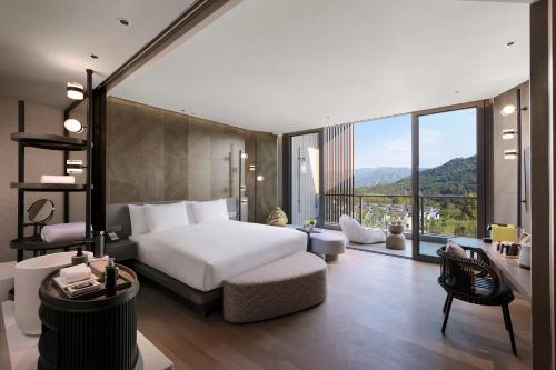 a bedroom with a white bed and a large window at Hotel Indigo Anji in Anji