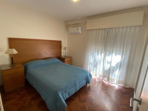 - une chambre avec un lit bleu et une fenêtre dans l'établissement Cómodo departamento en el centro de Mendoza, à Mendoza