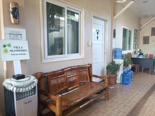 a wooden bench sitting in front of a building at Villa Skanderbeg Guest House in Puerto Princesa City