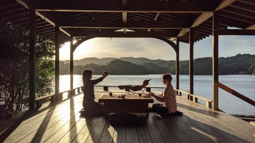 a woman and two girls sitting on a dock with a table at Hokyuann - 邦久庵 in Motogoe