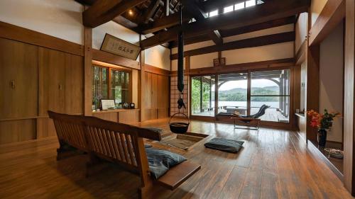 a living room with a bench and a large window at Hokyuann - 邦久庵 in Motogoe