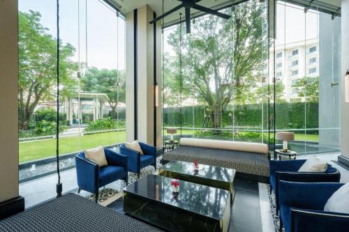 a lobby with blue chairs and a table and large windows at Somerset Pattaya in Pattaya Central