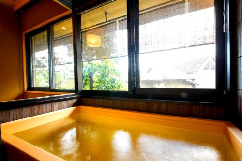 a bath tub in a room with a window at Kyoto Arashiyama Onsen Ryokan Togetsutei in Kyoto