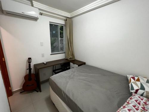 a bedroom with a bed and a guitar next to a window at Lua de Sossego - 3 quartos com Ar na praia dos milionários in Ilhéus
