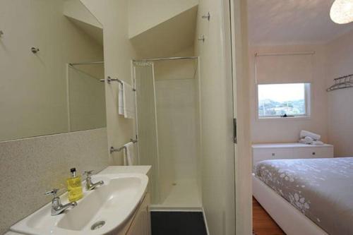 a bathroom with a sink and a bed and a mirror at Apollo Bay Rocket House l Pet-Friendly Free Wi-Fi in Apollo Bay