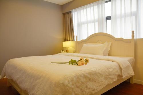 ein Schlafzimmer mit einem weißen Bett mit zwei Teddybären darauf in der Unterkunft 悠闲的时光 in Changsha
