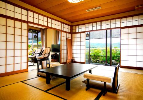 京都市にあるKyoto Arashiyama Onsen Ryokan Togetsuteiのテーブルと椅子、窓が備わる客室です。