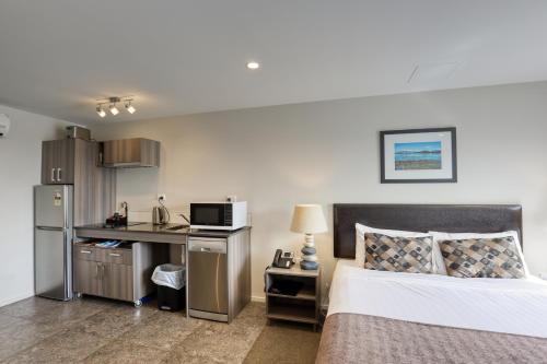 a bedroom with a bed and a desk with a microwave at Ramada Suites by Wyndham Queenstown Remarkables Park in Queenstown