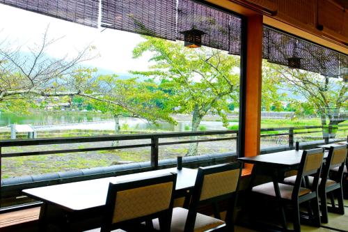 a restaurant with tables and chairs and a large window at Kyoto Arashiyama Onsen Ryokan Togetsutei in Kyoto