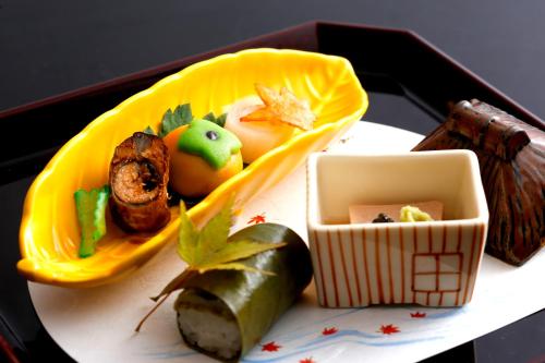 a plate of food on a table with someones food at Kyoto Arashiyama Onsen Ryokan Togetsutei in Kyoto
