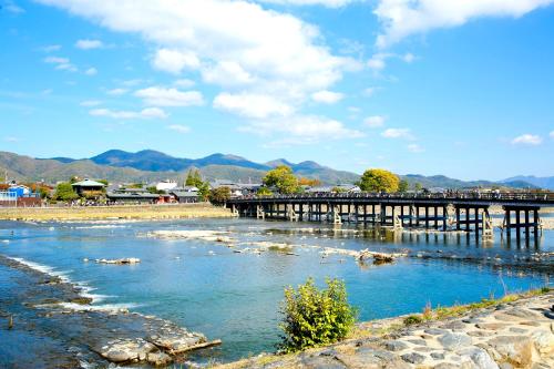 a bridge over a river with mountains in the background at Kyoto Arashiyama Onsen Ryokan Togetsutei in Kyoto