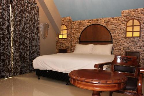 a bedroom with a bed and a table and a chair at Hi Kids B&B in Zhixue