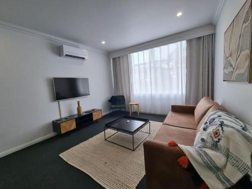 a living room with a couch and a flat screen tv at The Sherwood Hotel in Lismore