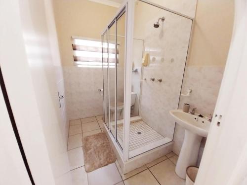 a bathroom with a shower and a sink at Rehoboth Guesthouse in Durban
