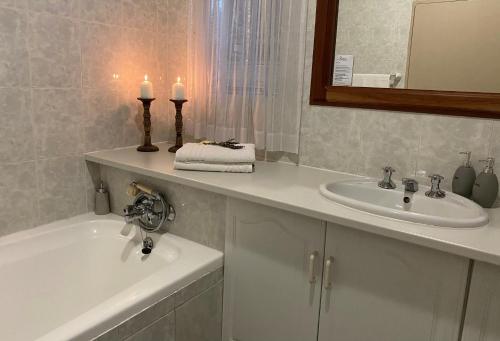 a bathroom with a sink and a tub and two candles at Anne's Place in Potchefstroom