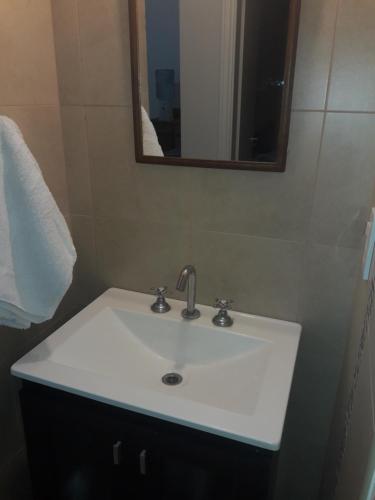lavabo blanco en el baño con espejo en Apart Soles II en Río Cuarto