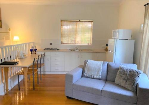 sala de estar con sofá, mesa y cocina en Granite Gardens Cottages & Lake Retreat, en Stanthorpe
