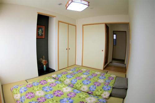 - une chambre avec un grand lit et une couverture colorée dans l'établissement Vegan Minshuku Sanbiki Neko, à Kyoto