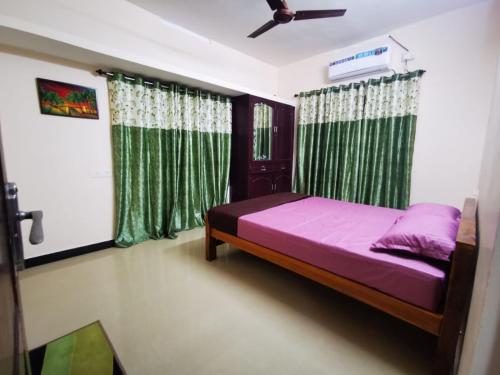 1 dormitorio con cama y cortinas verdes en J2 Home Stay - Luxury Homes with Caravan Services en Thiruvananthapuram