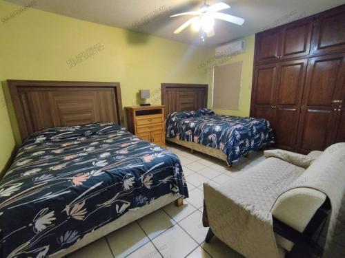 聖卡洛斯的住宿－Casa Villa Serena 5, enfrente de la alberca!，一间卧室配有两张床和椅子