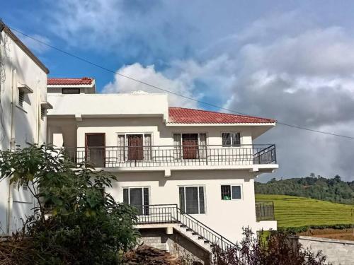 a white house with a balcony on top of it at Tea Estate view stay in Ooty