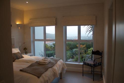 Plett Luxury Home في بليتنبيرغ باي: غرفة نوم بسرير ونوافذ كبيرة