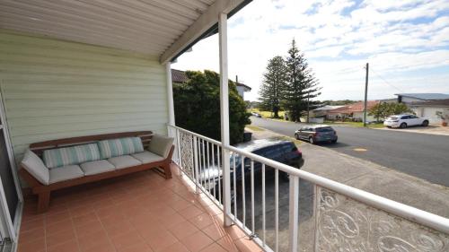 a porch with a bench on a balcony with a street at 1 5 Pilot Street Yamba in Yamba