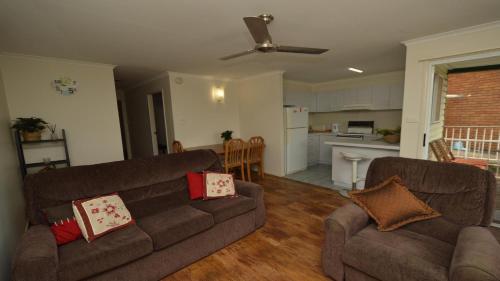 a living room with two couches and a kitchen at Unit 2 5 Pilot St Yamba in Yamba