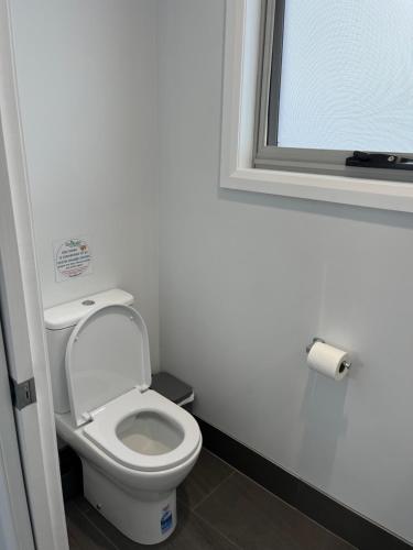 a white toilet in a bathroom with a window at Derby Digs Cabin in Derby