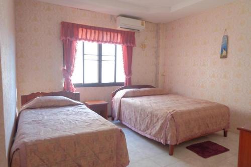 1 dormitorio con 2 camas y ventana en Thaveesinh Hotel, en Ban Houayxay
